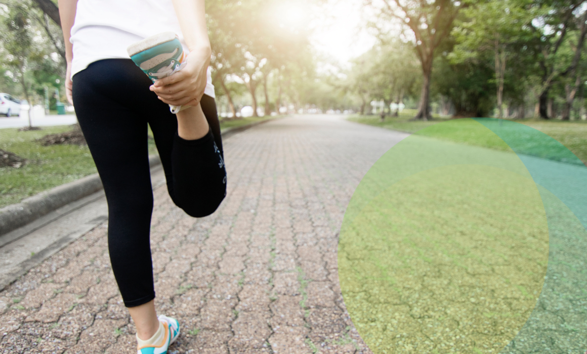 Lady in active wear doing a hamstring stretch outdoors